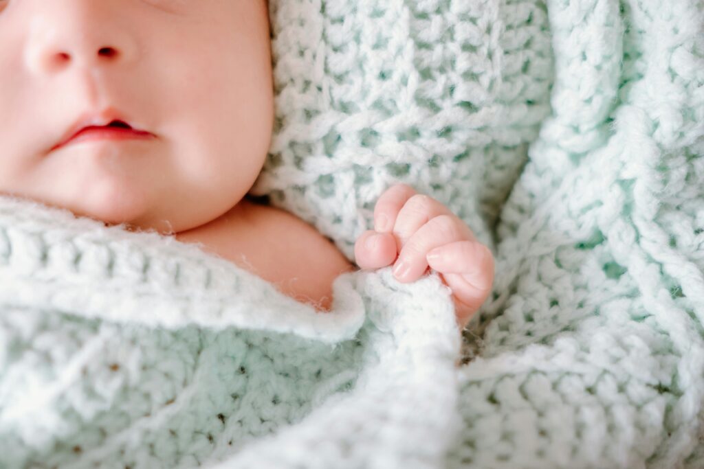 Adorable newborn baby wrapped in a cozy wool knit blanket, capturing peaceful innocence.